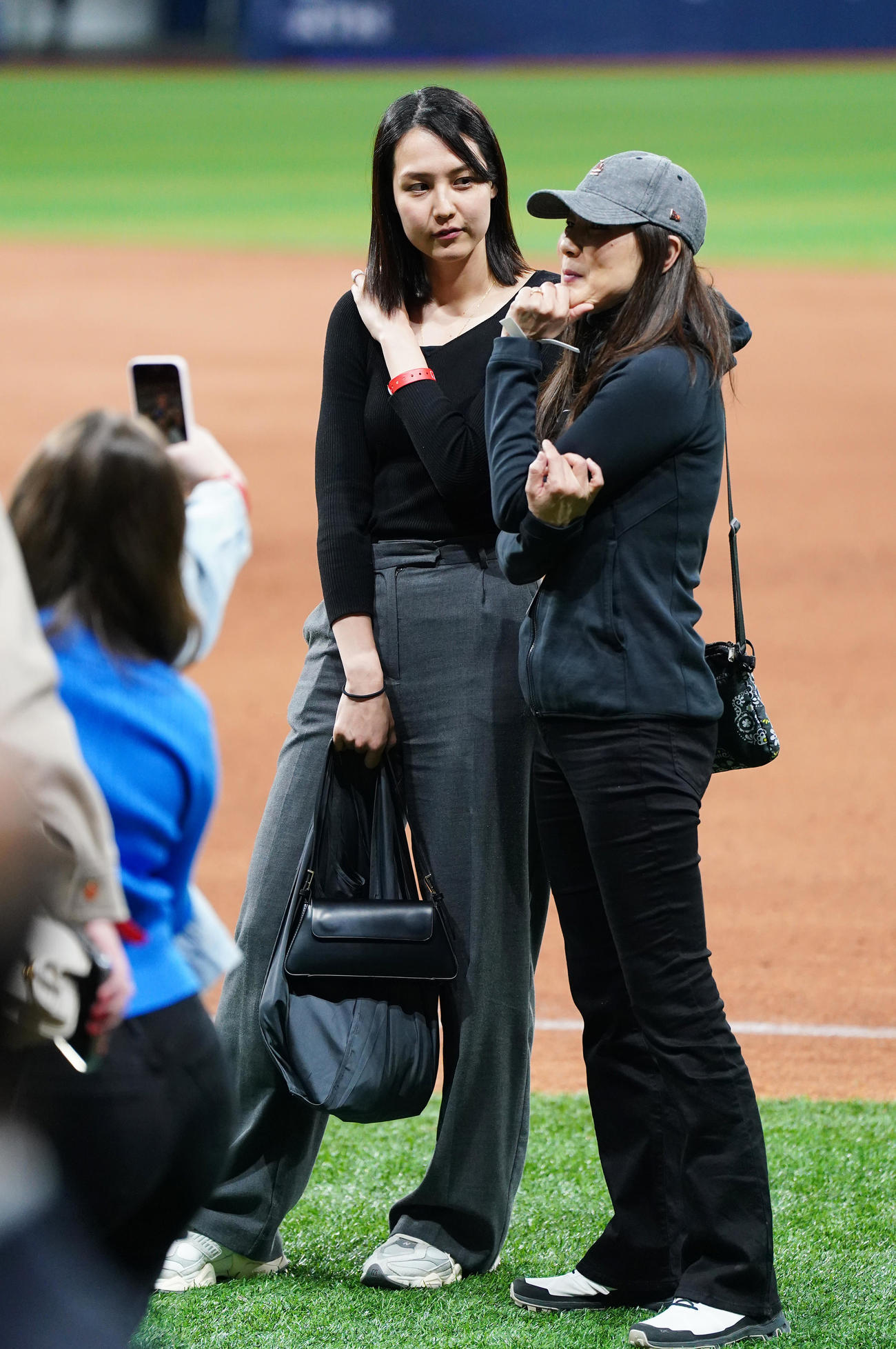 ドジャース対パドレス　試合後にフィールドで関係者と笑顔で話す真美子夫人（左）（撮影・菅敏）