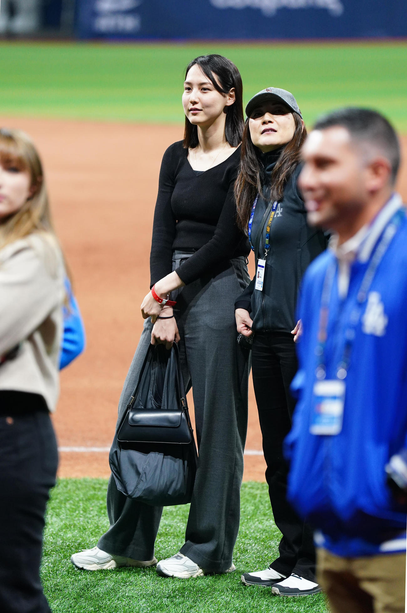 ドジャース対パドレス　試合後にフィールドで関係者と笑顔で話す真美子夫人（左）（撮影・菅敏）
