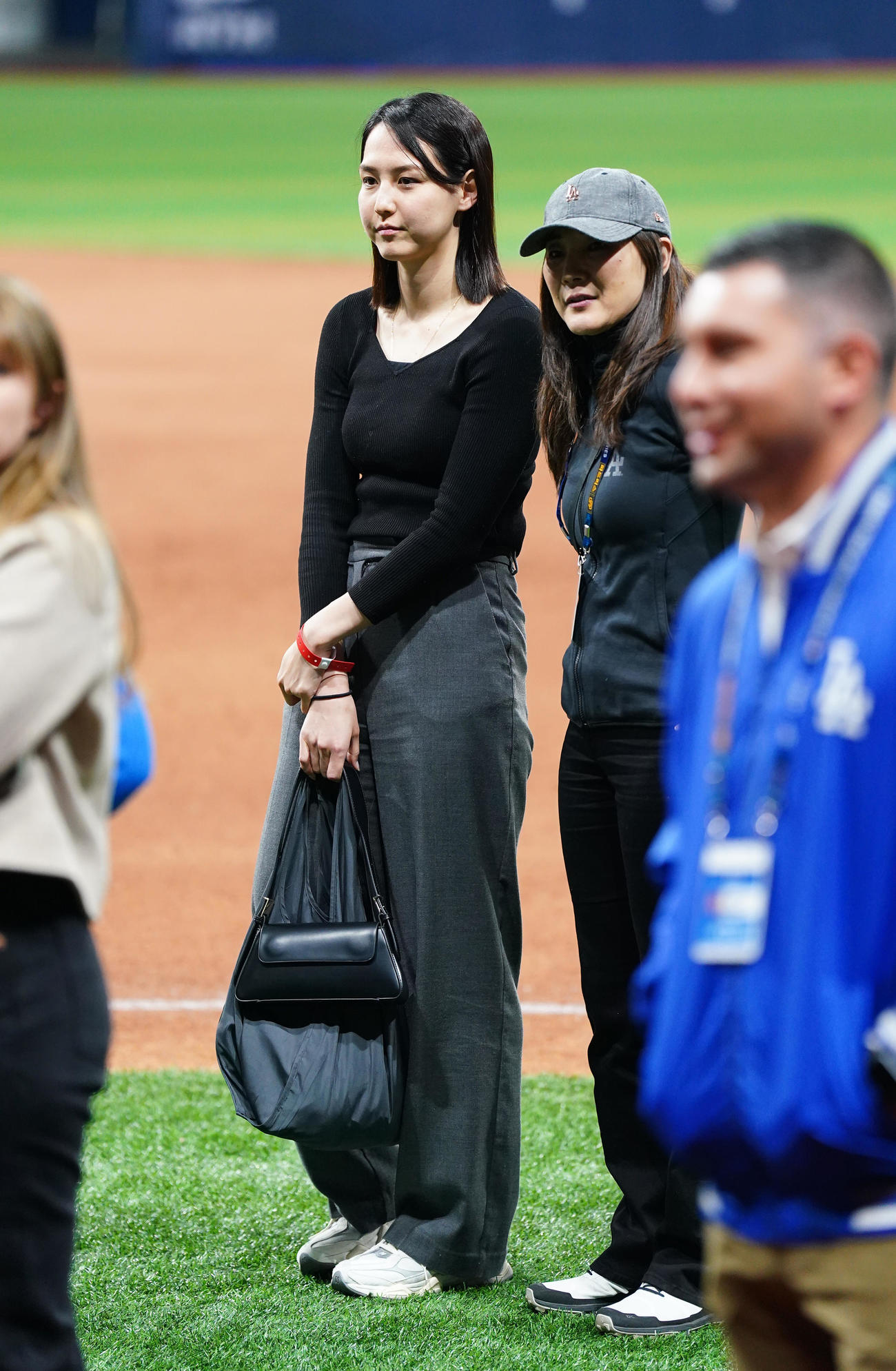 ドジャース対パドレス　試合後にフィールドで関係者と笑顔で話す真美子夫人（左）（撮影・菅敏）