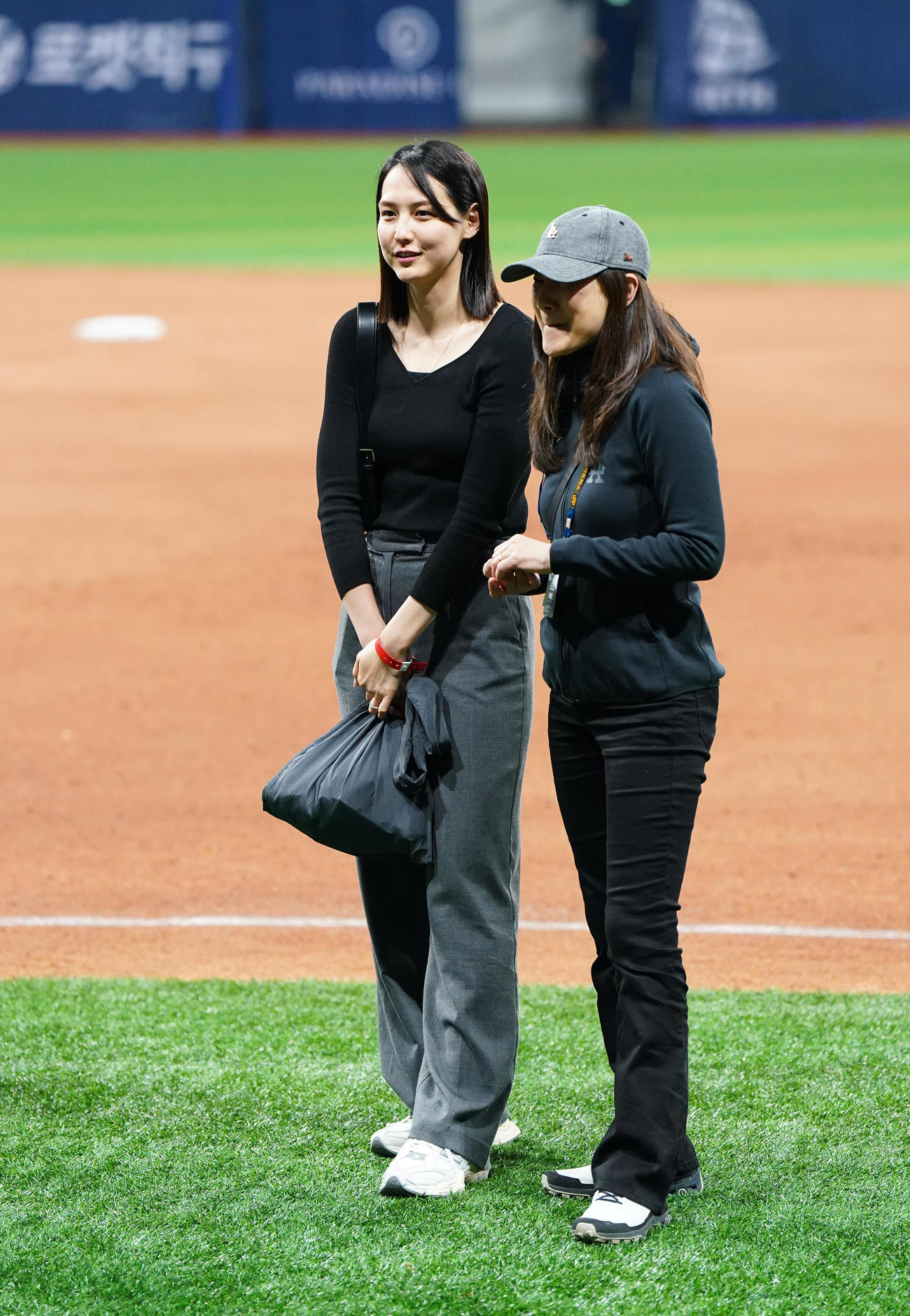 ドジャース対パドレス　試合後にフィールドで関係者と笑顔で話す真美子夫人（左）（撮影・菅敏）