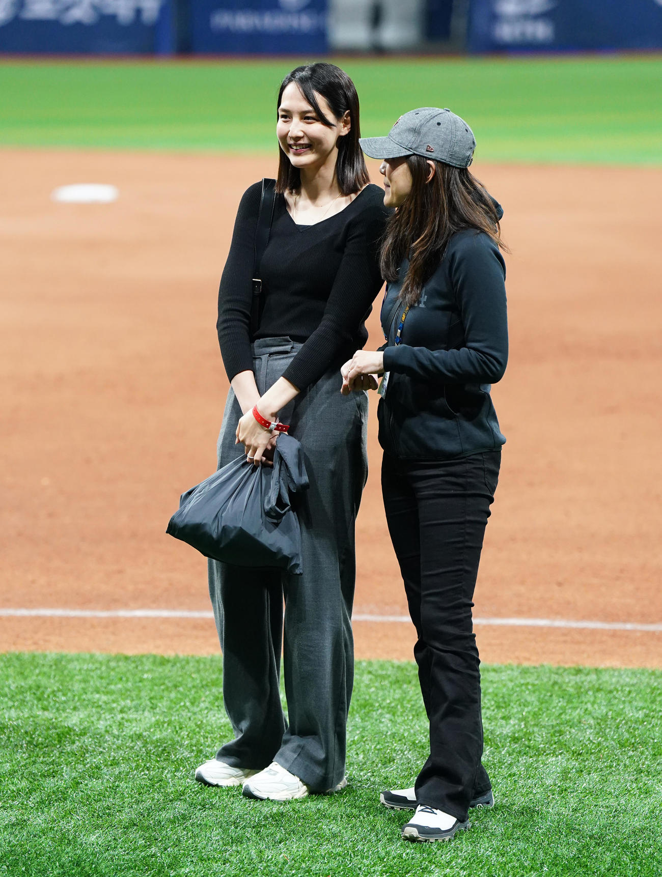 ドジャース対パドレス　試合後にフィールドで関係者と笑顔で話す真美子夫人（左）（撮影・菅敏）