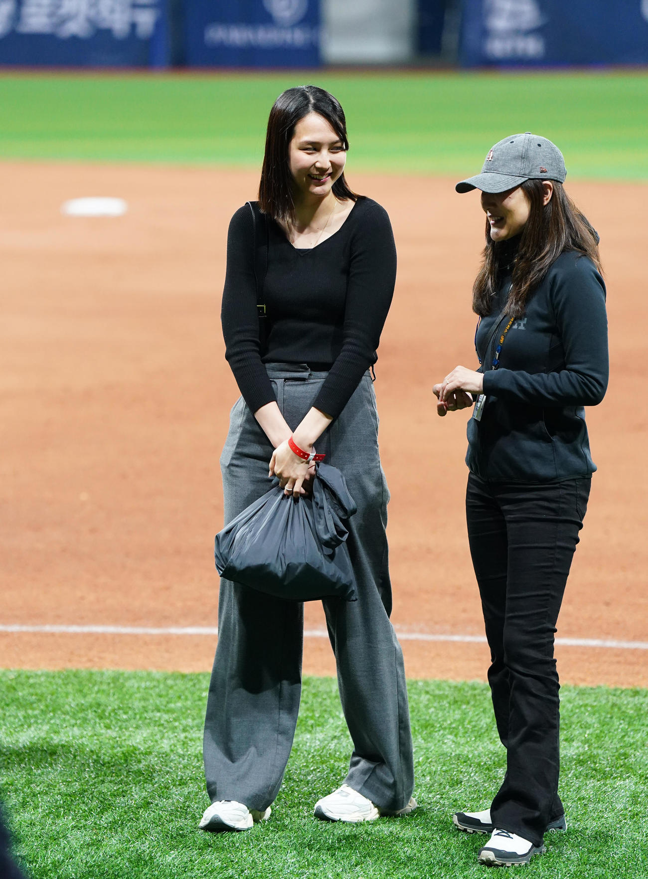 ドジャース対パドレス　試合後にフィールドで関係者と笑顔で話す真美子夫人（左）（撮影・菅敏）