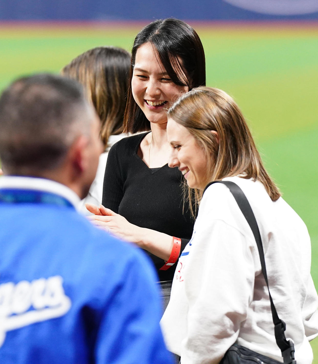 ドジャース対パドレス　試合後にフィールドで関係者と笑顔で話す真美子夫人（中央）（撮影・菅敏）