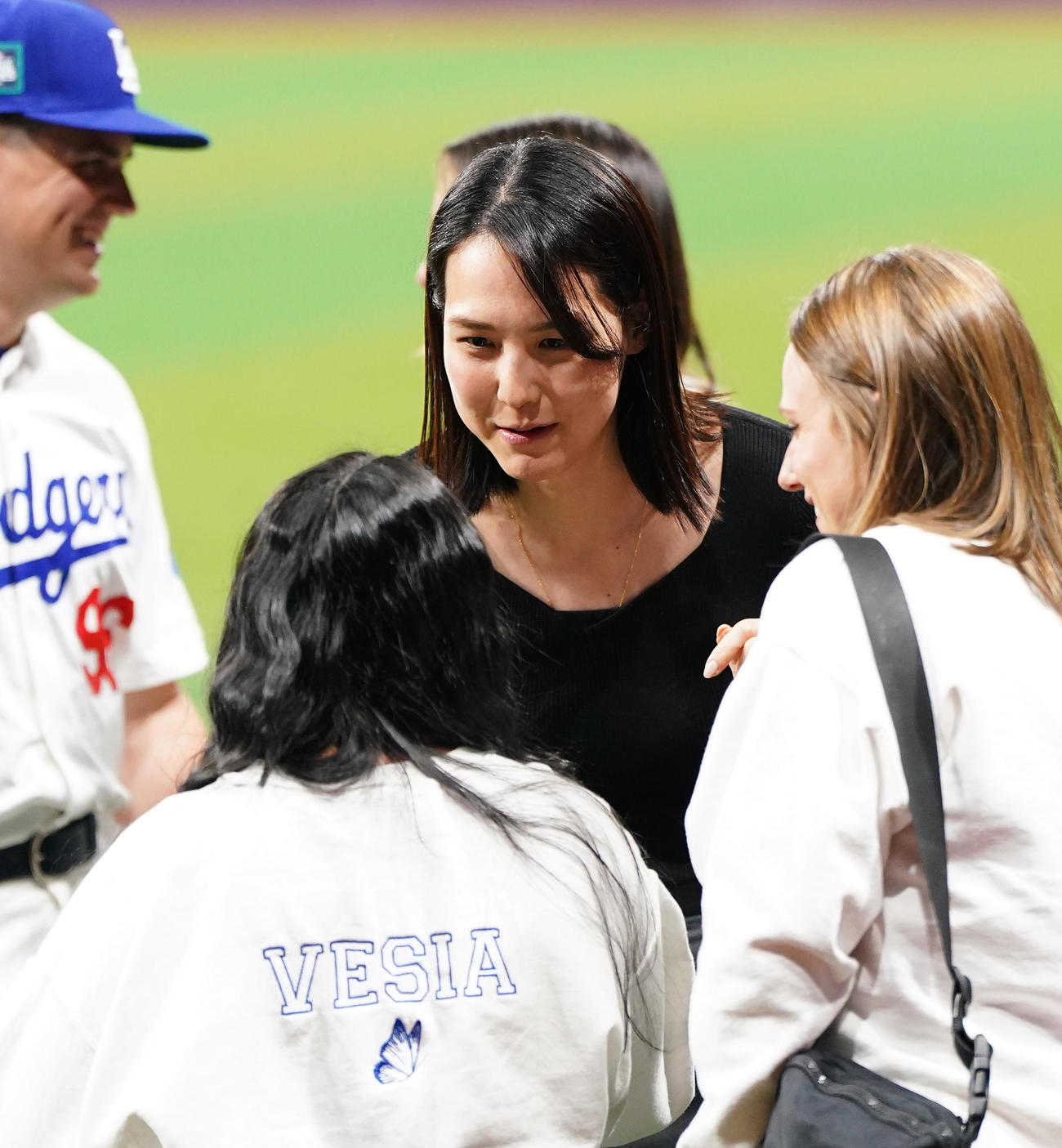 ドジャース対パドレス　試合後にフィールドで関係者と笑顔で話す真美子夫人（左）（撮影・菅敏）