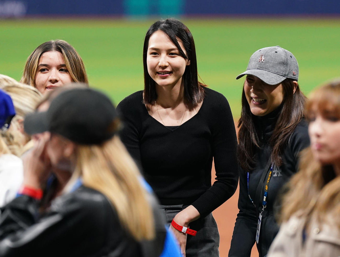 ドジャース対パドレス　試合後にフィールドで関係者と笑顔で話す真美子夫人（中央）（撮影・菅敏）