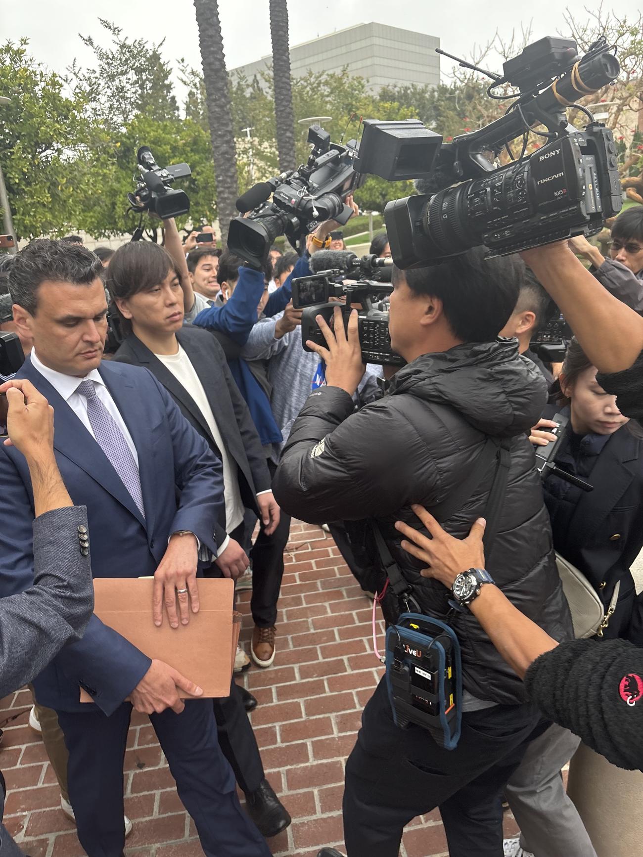 2度目の審理を終え、連邦地裁から引き揚げる際、多くの報道陣に囲まれる水原被告（左から2人目）。手前左はフリードマン弁護士（撮影・斎藤庸裕）