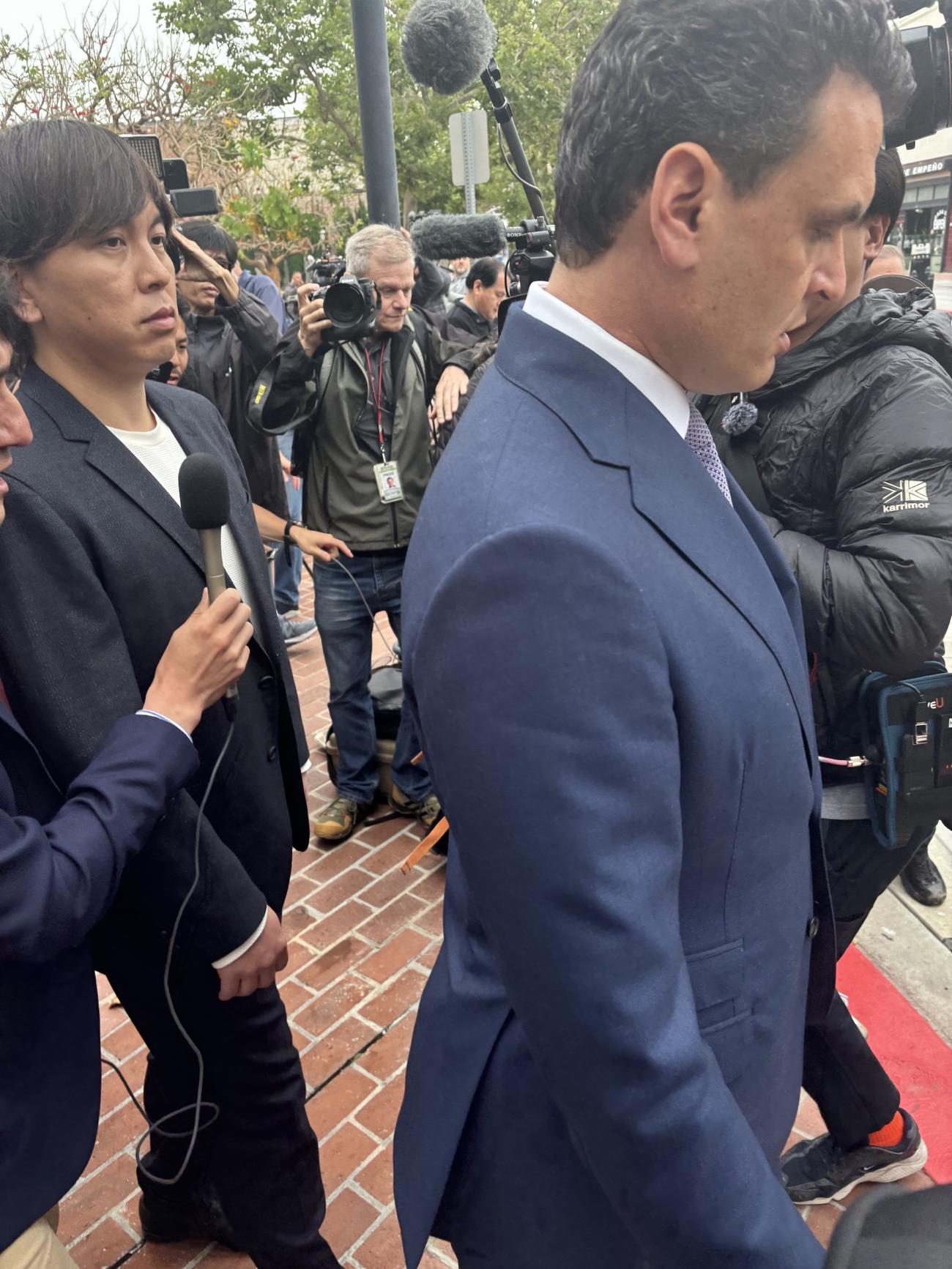 2度目の審理を終え、連邦地裁から引き揚げる際、多くの報道陣に囲まれる水原被告（左）。手前はフリードマン弁護士（撮影・斎藤庸裕）