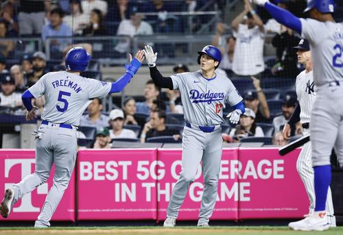 ヤンキース対ドジャース　11回表ドジャース1死一、二塁、T・ヘルナンデス　37の2点適時二塁打で生還し、フリーマン（左）とタッチを交わす大谷（撮影・藤尾明華）
