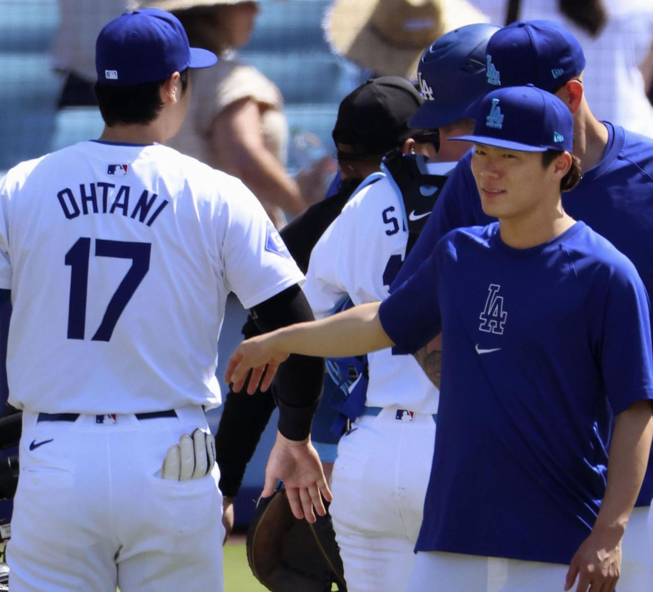 ロイヤルズに勝利し、タッチを交わすドジャース大谷（左）と山本（共同）