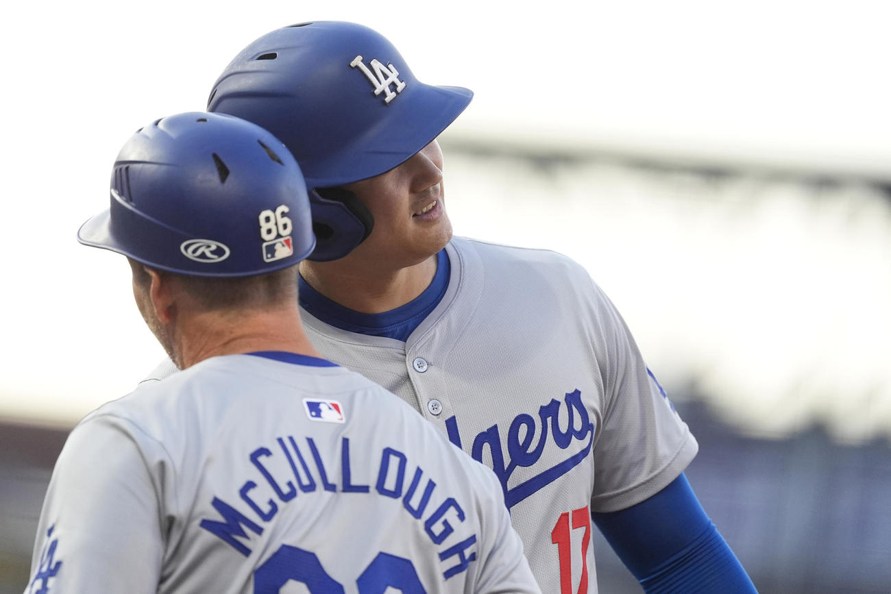 大谷翔平はロッキーズ戦の1回表、安打で出塁後、一塁コーチとヘルメットを当てて喜ぶ（AP)