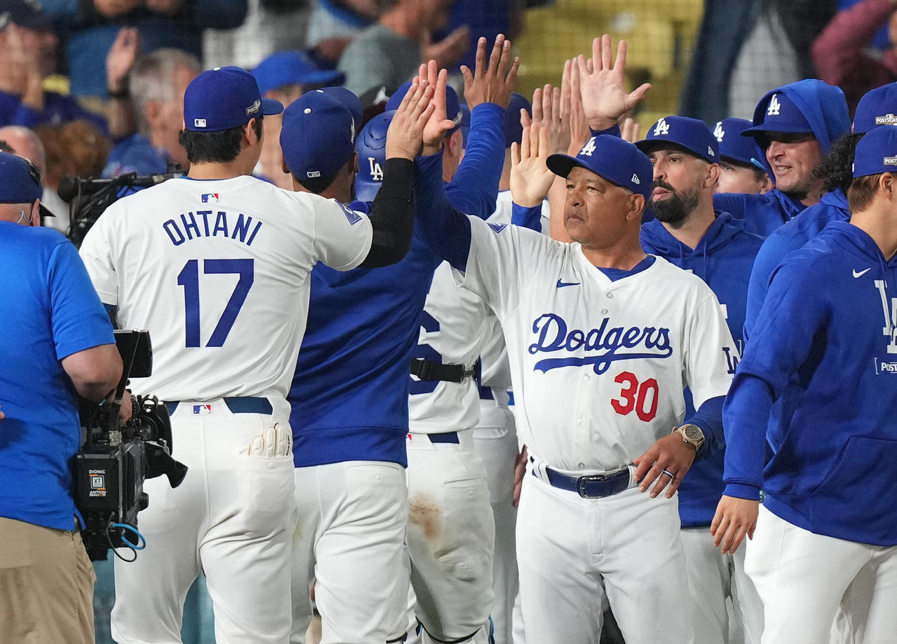 デビジョンシリーズ初戦を白星で飾り、大谷（左）をタッチで迎えるロバーツ監督（撮影・菅敏）