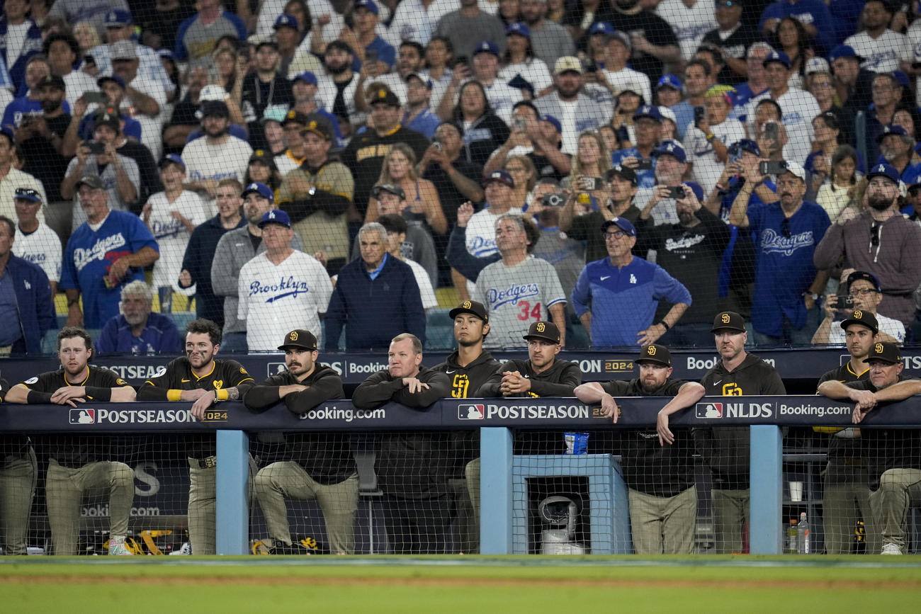 ドジャース対パドレス　グラウンドで喜ぶドジャースナインをベンチから見つめるパドレスの選手たち（AP）
