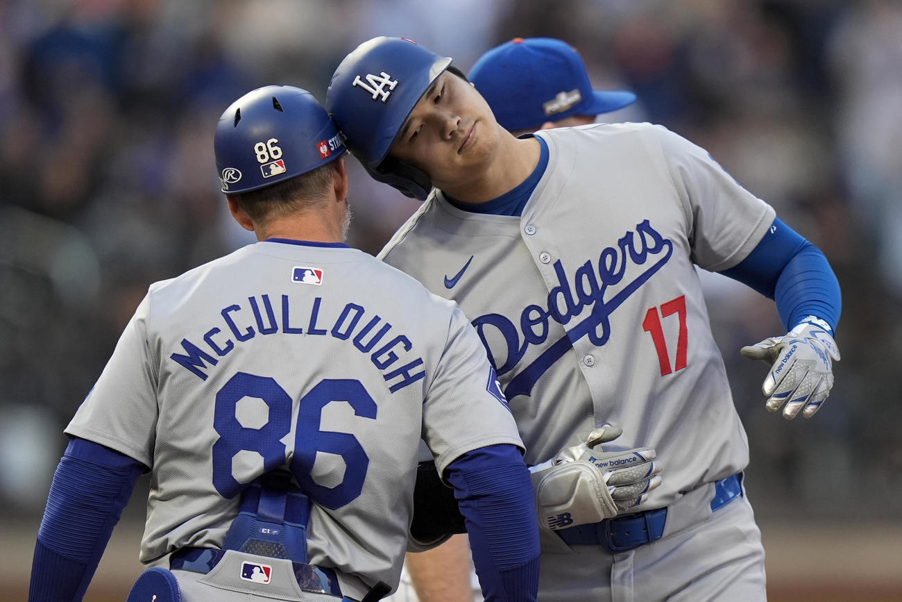 大谷翔平は1回の第1打席で安打を放つと一塁コーチとヘルメットを叩き合って喜ぶ（AP)