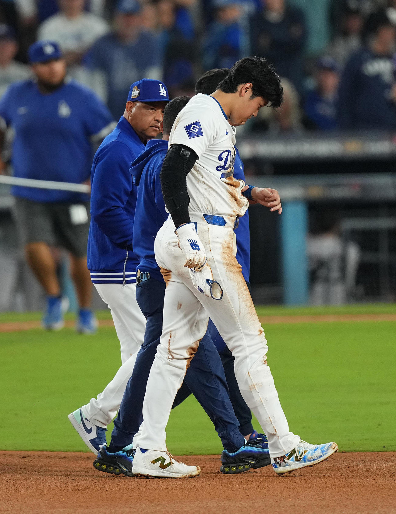 ドジャース対ヤンキース　7回裏ドジャース2死一塁、二塁盗塁を狙うもアウトとなった大谷は、左手を負傷しロバーツ監督（後方）に付き添われベンチに戻る（撮影・菅敏）