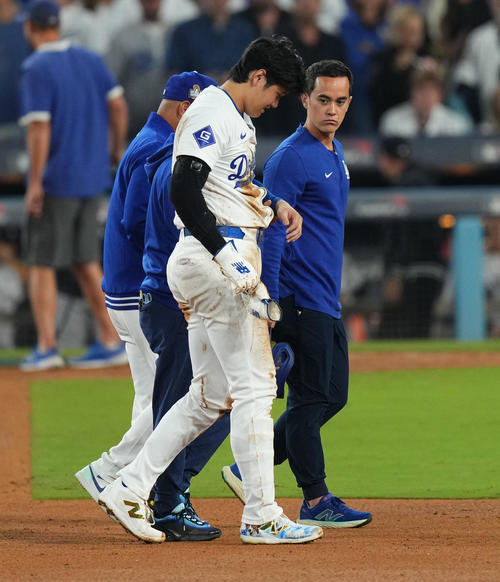 ドジャース対ヤンキース　7回裏ドジャース2死一塁、二塁盗塁を狙うもアウトとなった大谷は、左手を負傷しロバーツ監督（後方）に付き添われベンチに戻る（撮影・菅敏）