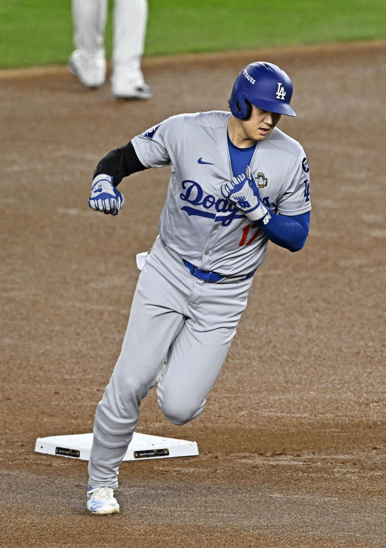 ヤンキース戦の1回、四球で出塁し、フリーマンの先制2ランで生還するドジャース大谷は、左肩を固定するために首元をつかみながら走塁した＝ニューヨーク（共同）