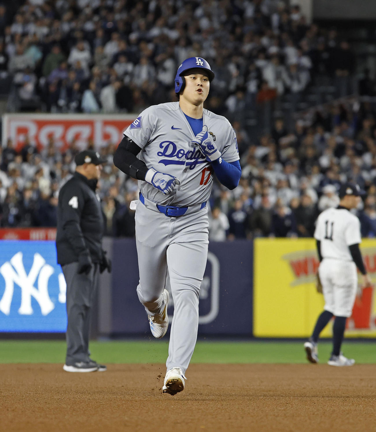 ヤンキース戦の1回、四球で出塁し、フリーマンの先制2ランで首元をつかんで左肩を固定しながら走り生還するドジャース大谷＝ニューヨーク（共同）