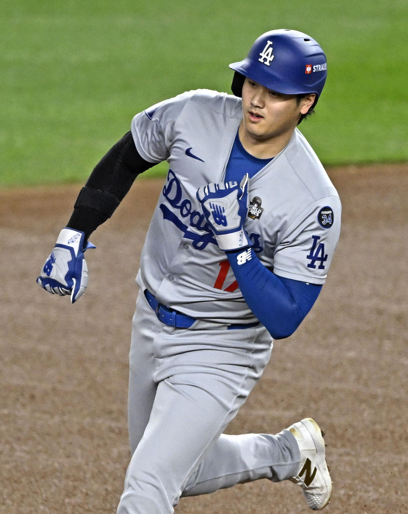 フリーマンの先制2ランで生還するドジャース大谷。左手でユニホームの胸元をつかんで肘を曲げたまま走っている（共同）
