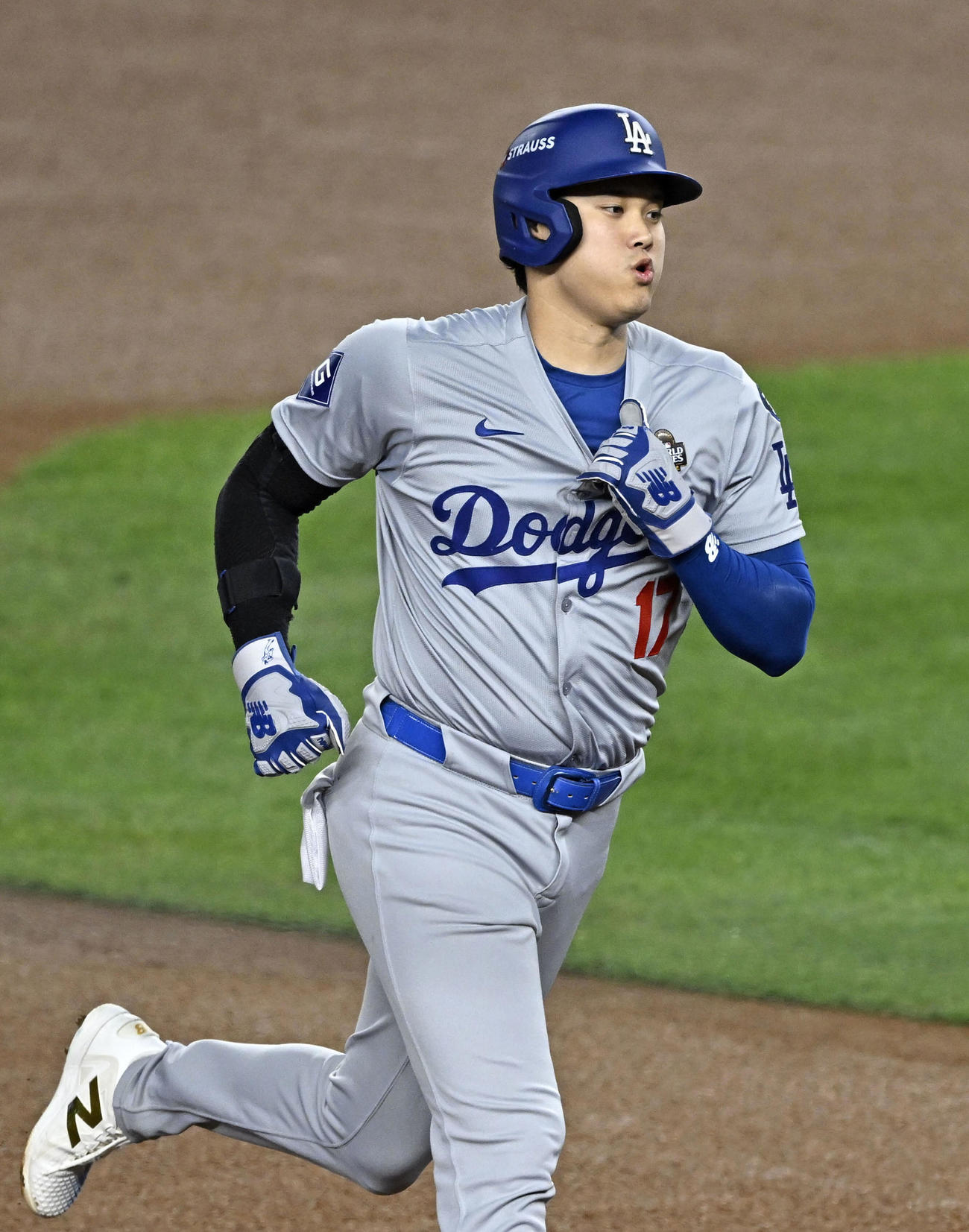 フリーマンの先制2ランで生還するドジャース大谷。左手でユニホームの胸元をつかんで肘を曲げたまま走っている（共同）