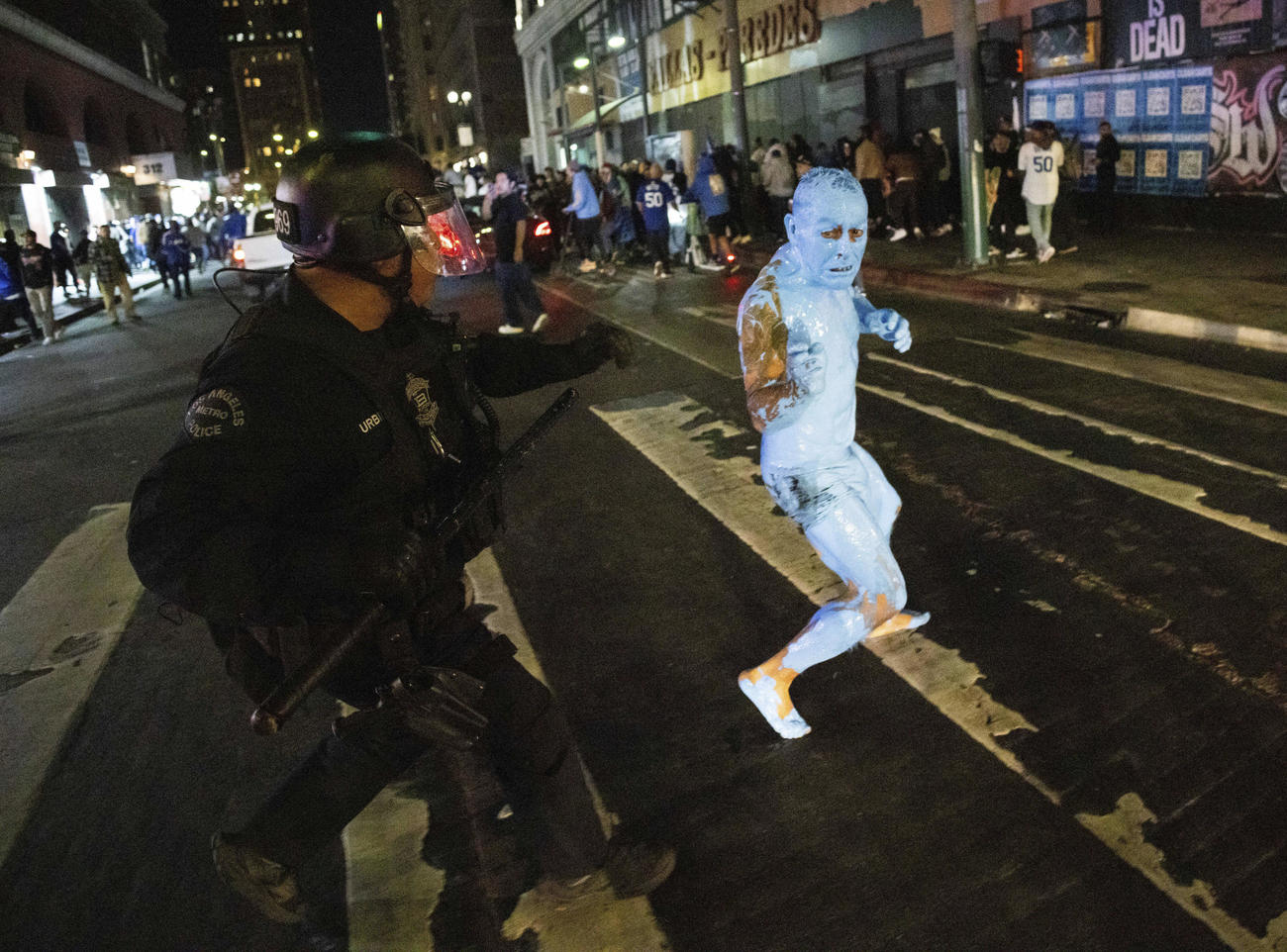 警官に追われる全身を青くペイントしたファン（AP)