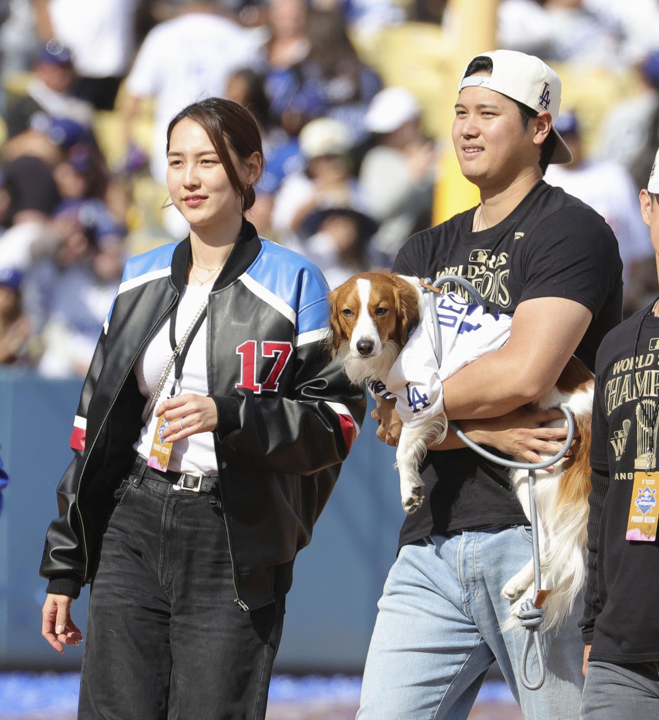 ドジャースタジアムで行われた優勝報告会を終え、愛犬デコピンを抱いて引き揚げる米大リーグ、ドジャースの大谷翔平と妻の真美子さん＝1日、ロサンゼルス（共同）