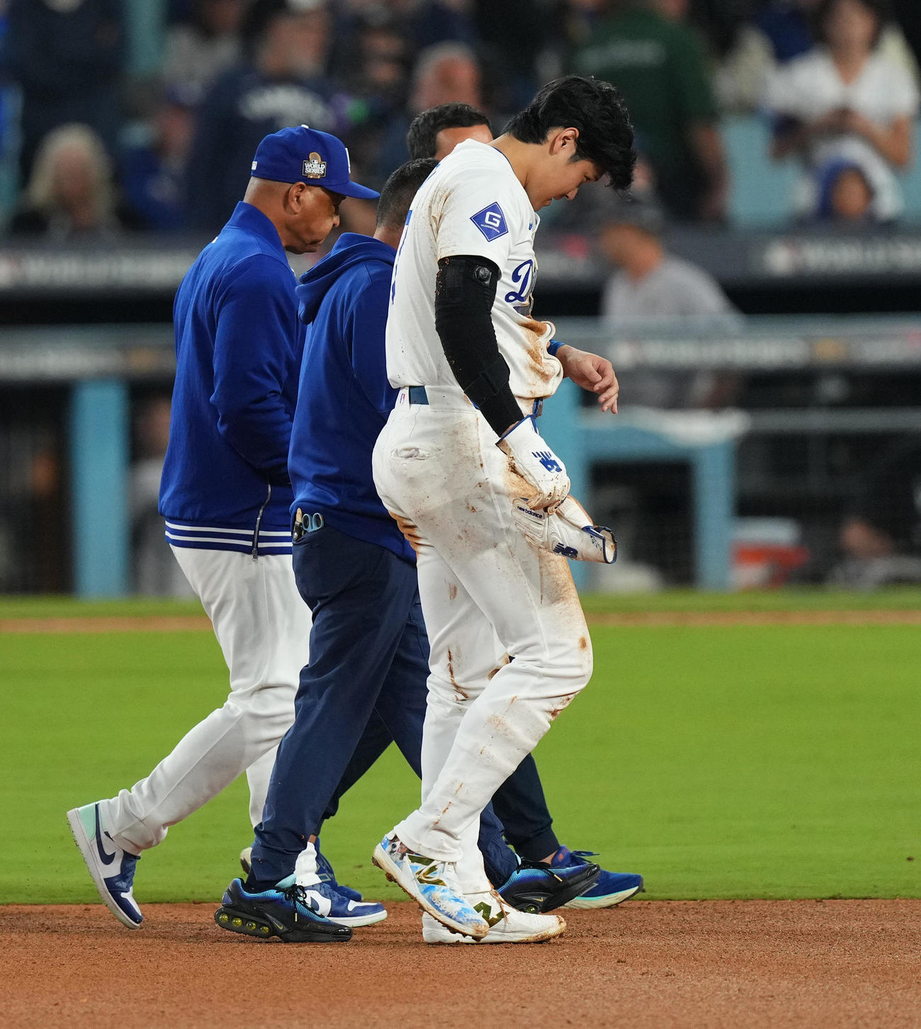 ドジャース対ヤンキース　7回裏ドジャース2死一塁、二塁盗塁を狙うもアウトとなった大谷は、左肩を脱臼し、ロバーツ監督（左）に付き添われベンチに戻る（2024年10月26日）