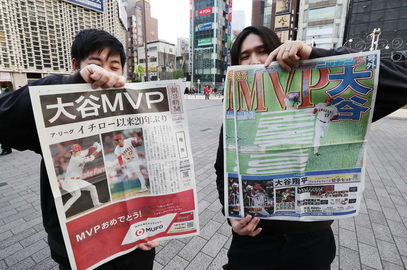 2021年11月、エンゼルス大谷のMVP選出を報じる日刊スポーツ号外（右）と朝日新聞の号外を掲げる人たち