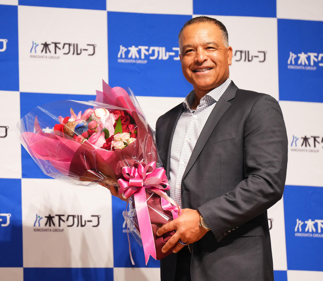 木下グループの新CMに出演し、制作発表会で受け取った花束を手に笑顔を見せるドジャース・ロバーツ監督（撮影・菅敏）