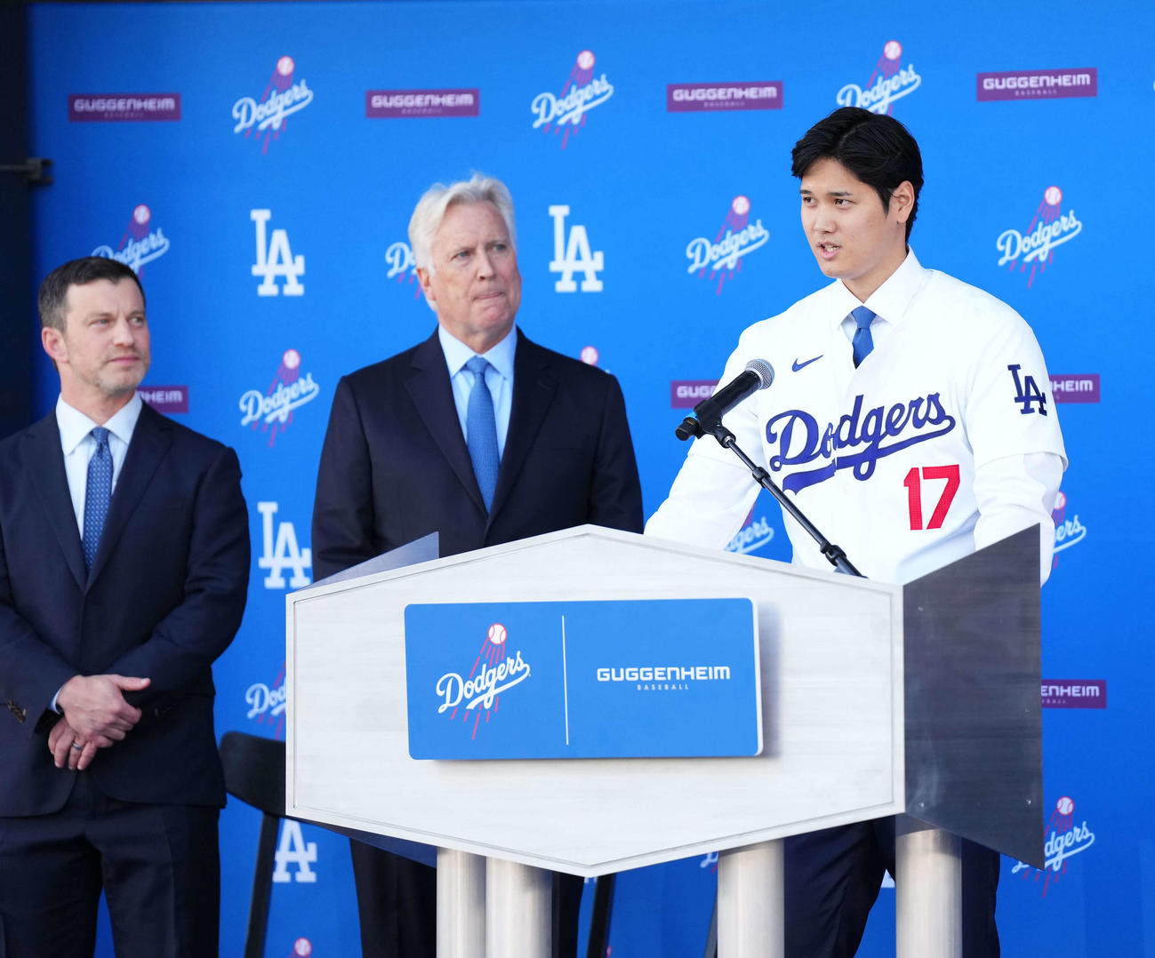 ドジャース入団会見　スピーチする大谷翔平。左からアンドリュー・フリードマン編成本部長、球団オーナーのマーク・ウォルター氏、1人おいて水原一平通訳=2023年12月14日（現地時間）
