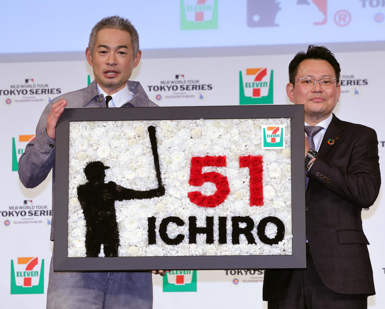 「セブン－イレブン・ジャパン×MLBパートナーシップ契約」記者発表会に登場したイチロー氏（左）は、セブン－イレブン・ジャパンの岡嶋マーケティング本部長から殿堂入りを祝ったブリザーブドフラワーを贈られる（撮影・野上伸悟）