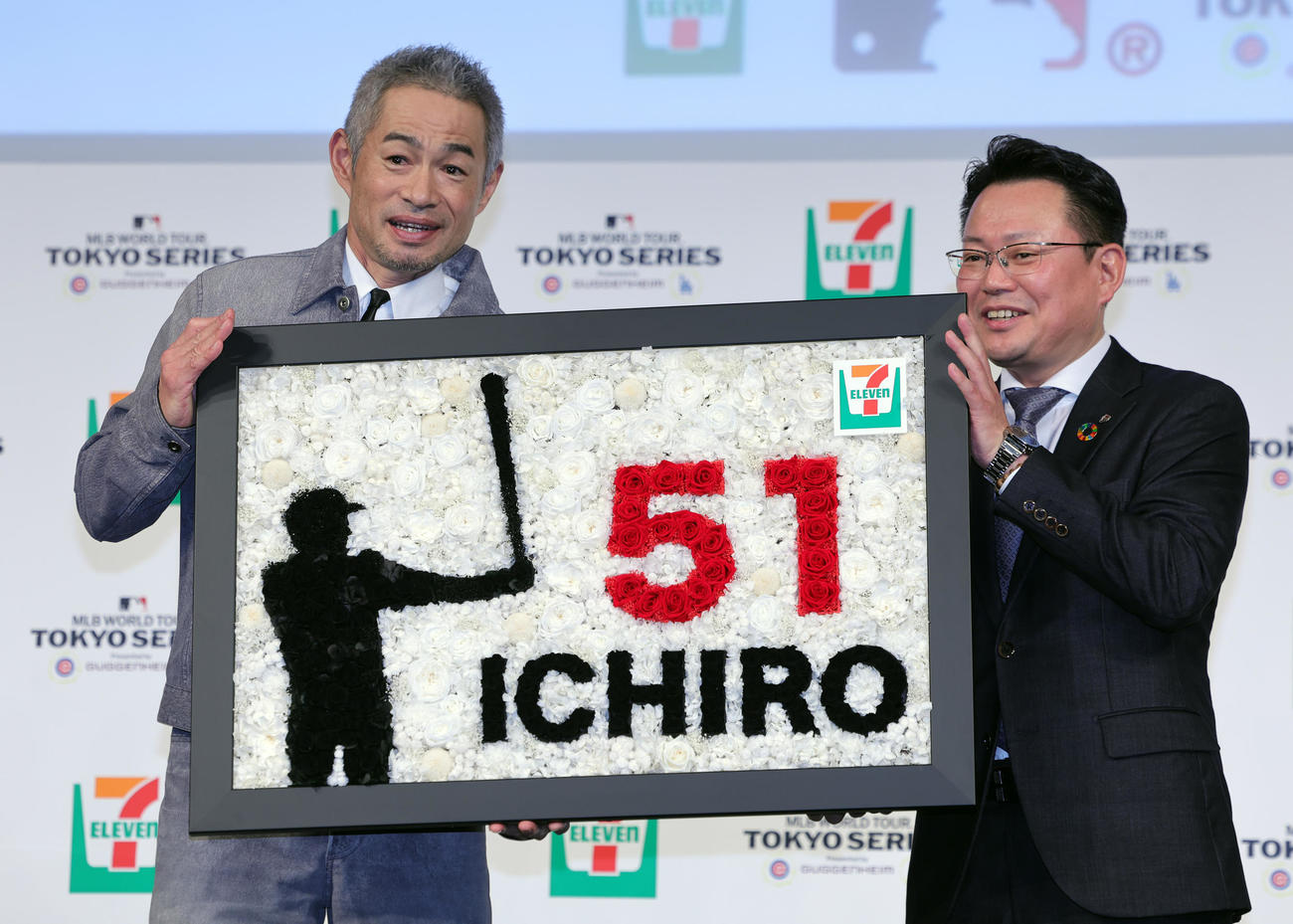 「セブン－イレブン・ジャパン×MLBパートナーシップ契約」記者発表会に登場したイチロー氏（左）は、セブン－イレブン・ジャパンの岡嶋マーケティング本部長から殿堂入りを祝ったブリザーブドフラワーを贈られる（撮影・野上伸悟）