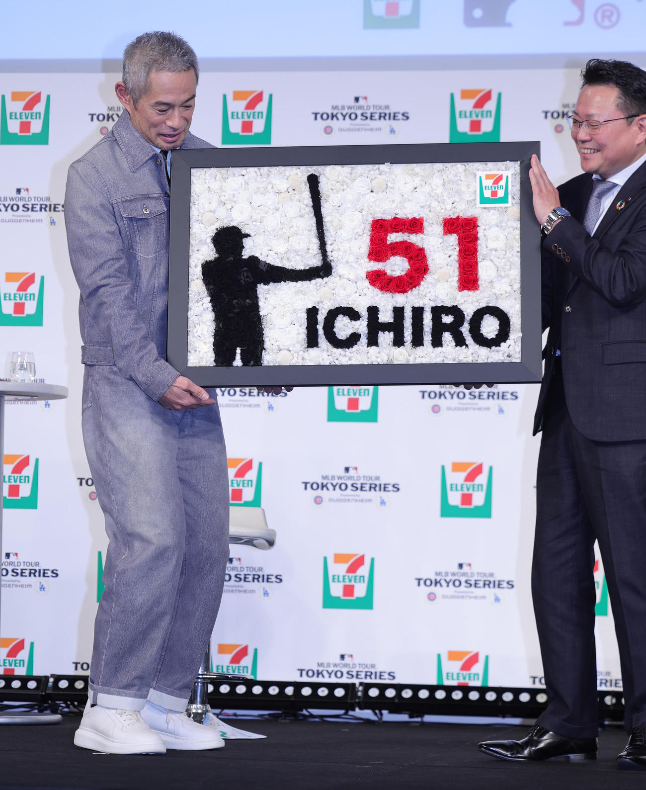 「セブン－イレブン・ジャパン×MLBパートナーシップ契約」記者発表会に登場したイチロー氏（左）は、セブン－イレブン・ジャパンの岡嶋マーケティング本部長から殿堂入りを祝ったプリザーブドフラワーを贈られる（撮影・野上伸悟）