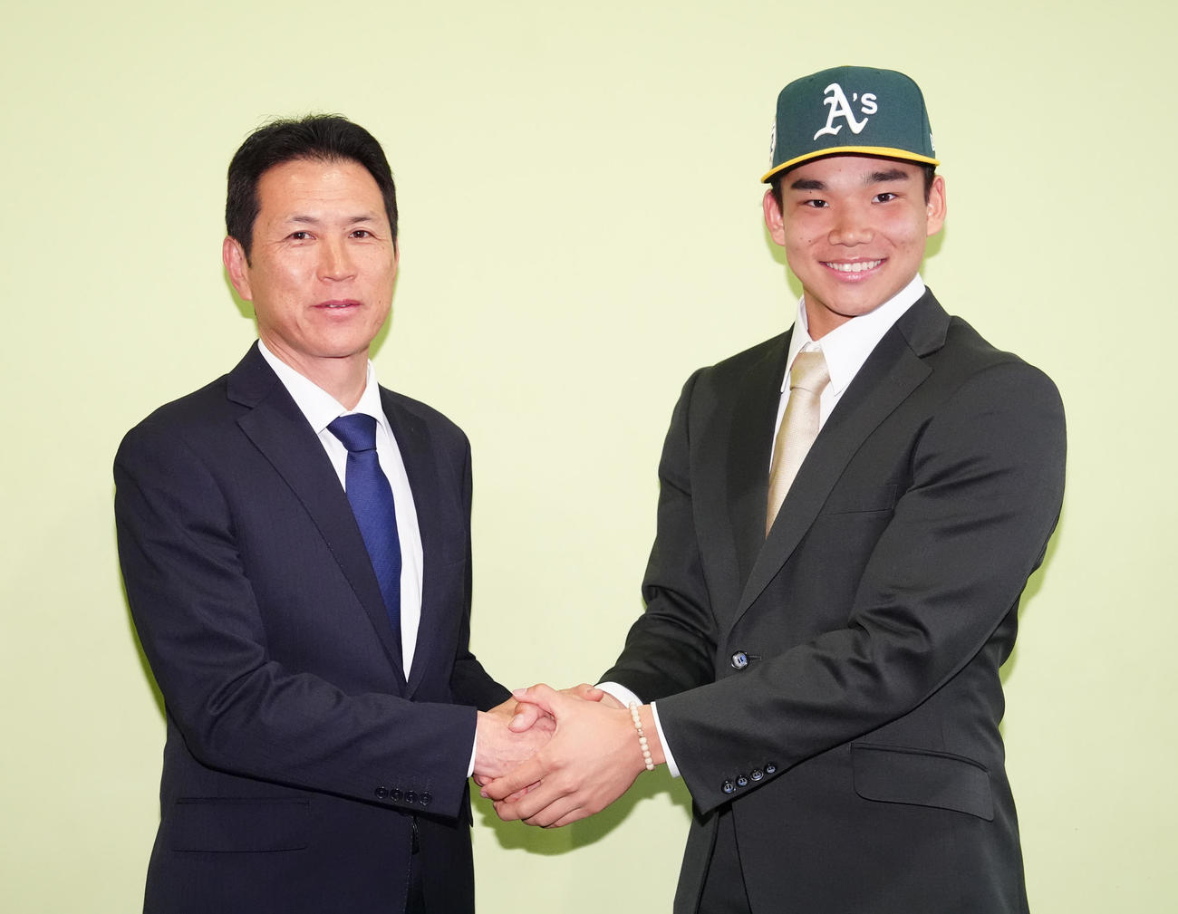 会見後、アスレチックスの帽子をかぶり田中監督（左）と握手を交わす桐朋・森井（撮影・江口和貴）