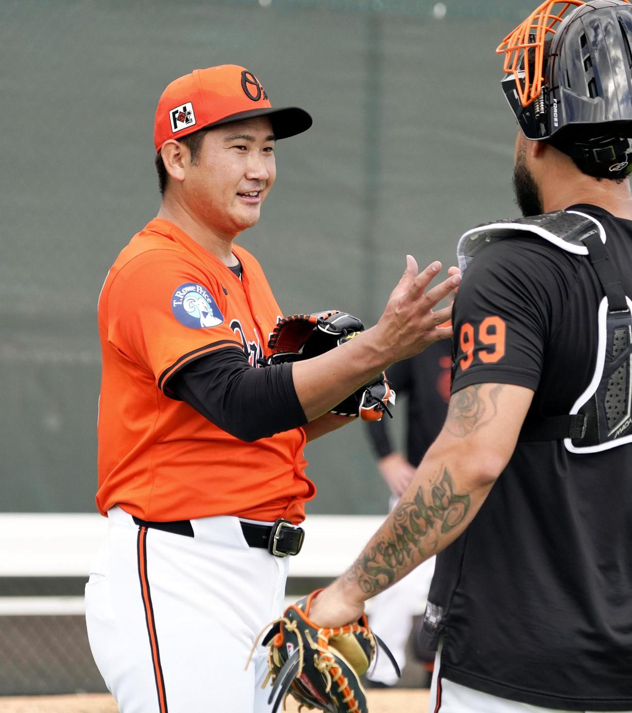 投球練習を終え、捕手とタッチを交わすオリオールズ菅野（共同）