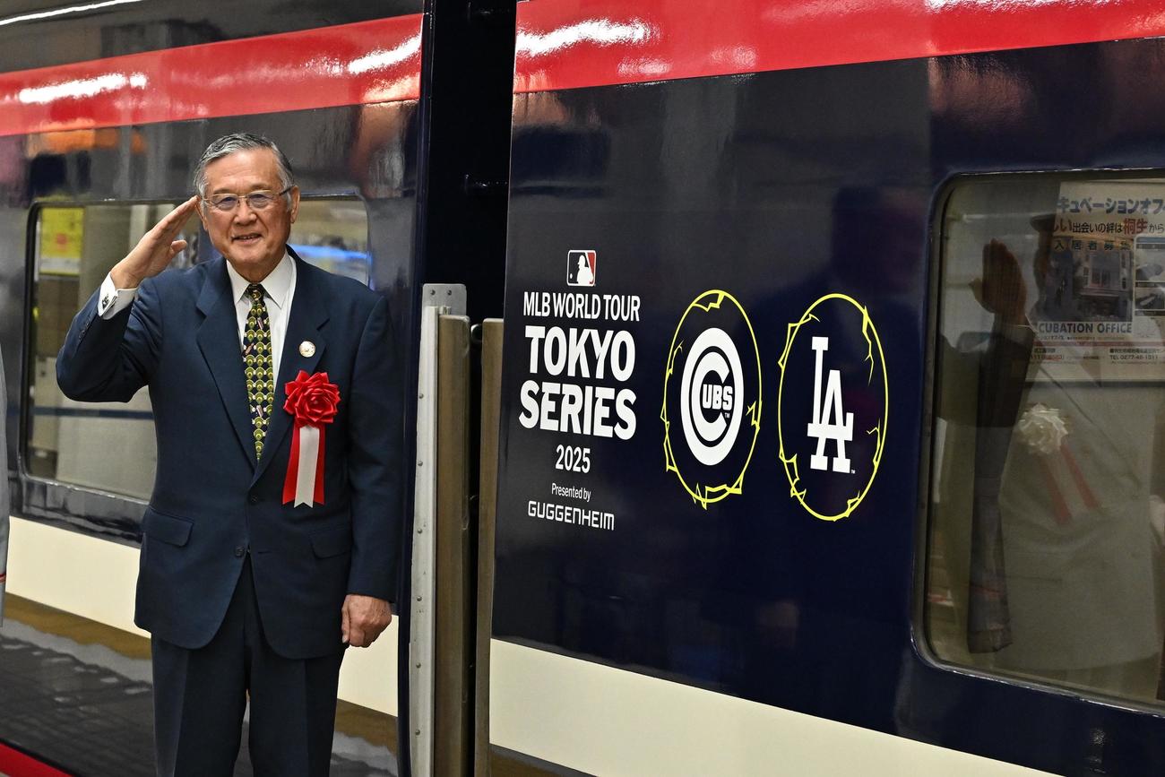 MLBカラーにラッピングされた列車の前で記念撮影するマッシー村上氏（撮影・滝沢徹郎）