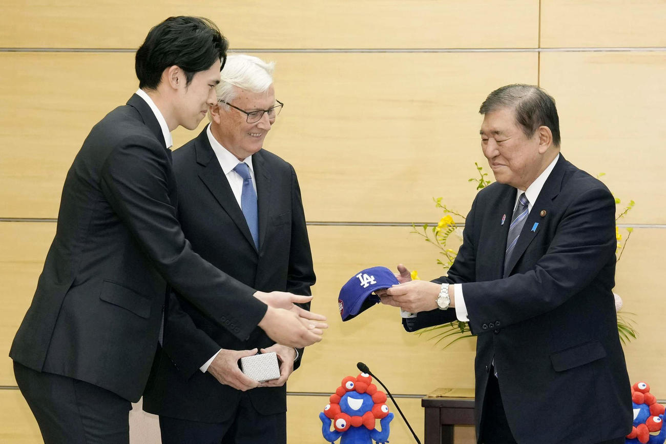 米大リーグ・ドジャースの佐々木朗希（左）から、ドジャースキャップを贈呈される石破首相（共同）