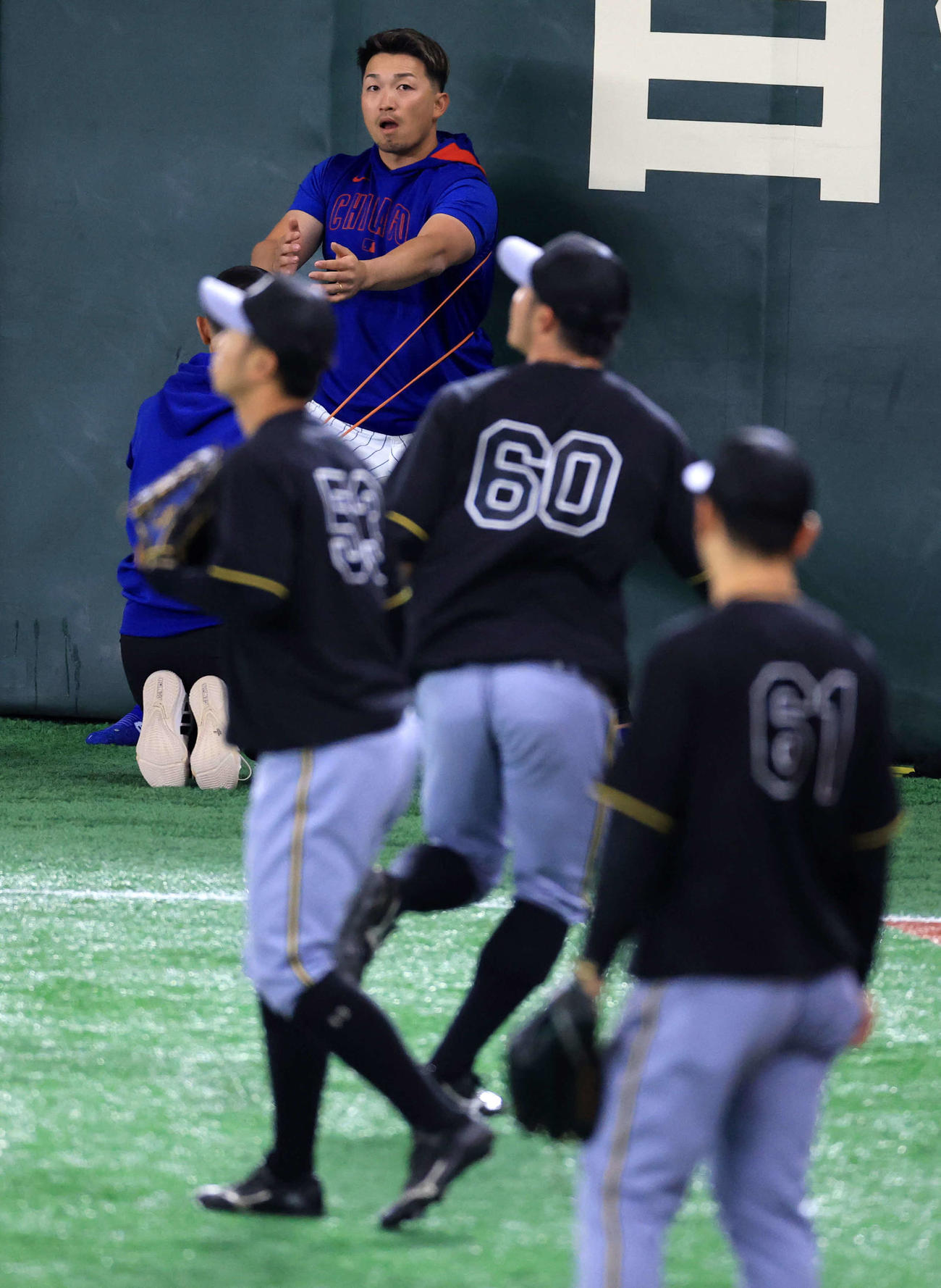 阪神対カブス　試合前練習をする阪神の選手たちを見ながらウオームアップするカブス鈴木（撮影・浅見桂子）