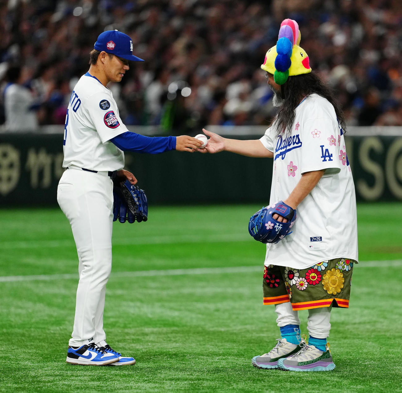 巨人対ドジャース　試合前、始球式に臨み、捕手役を務めたドジャース山本（左）からボールを受け取る村上隆氏（撮影・江口和貴）
