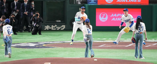 阪神対ドジャース　始球式でMISAMOのSANA（手前中央）の球を受けるドジャース佐々木（右奥）（撮影・鈴木みどり）