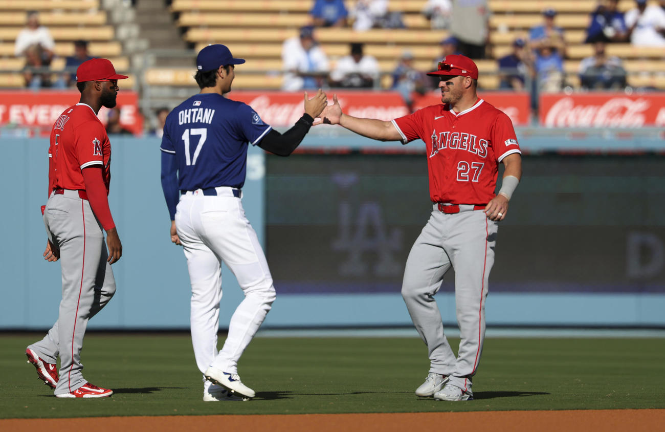 試合前、エンゼルスのトラウト（右）とタッチを交わすドジャース大谷。左はアデル（AP）