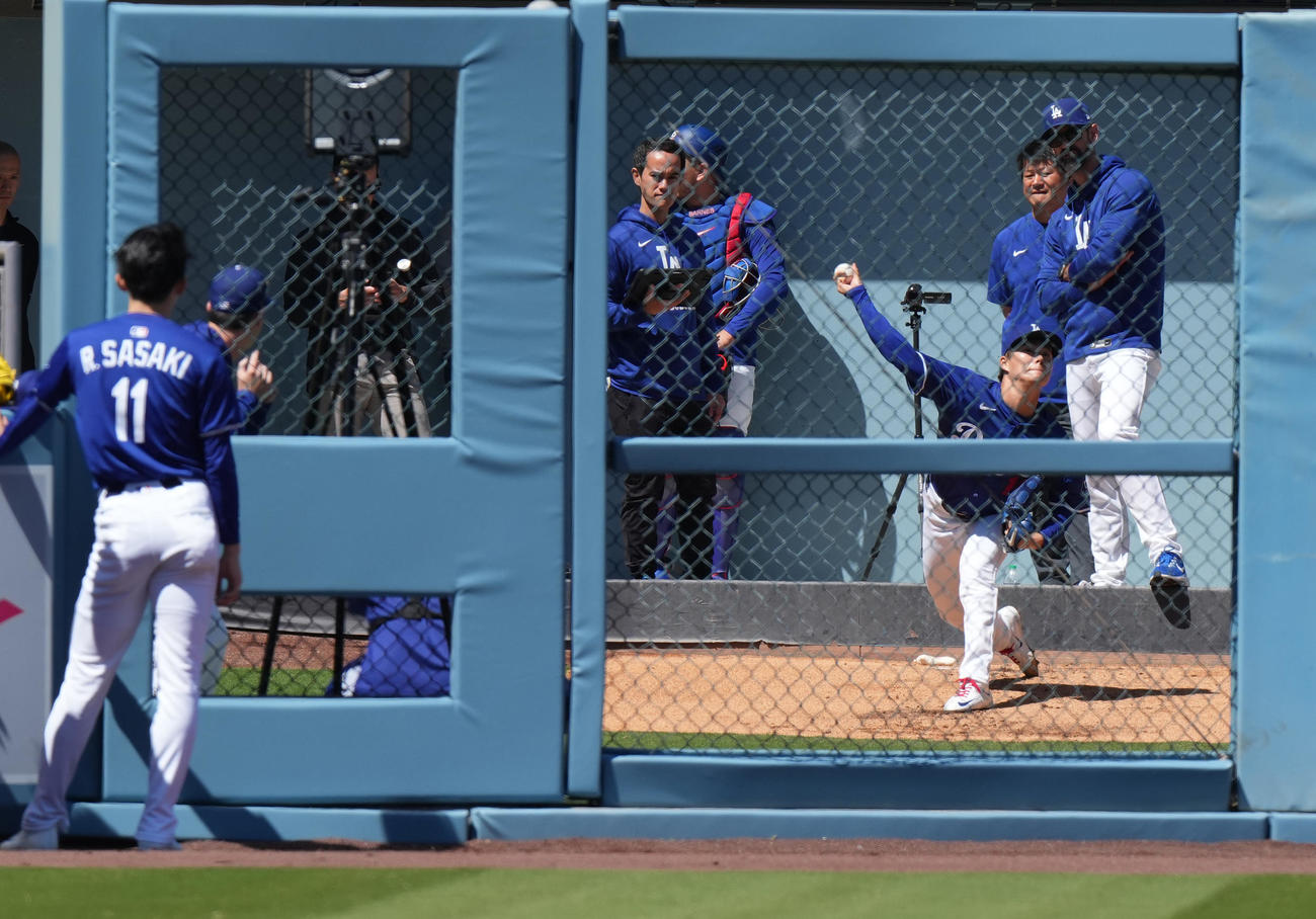 ドジャース対ブレーブス　試合前、ブルペンで佐々木（左手前）の視線を受けながら投球練習をする山本（撮影・菅敏）