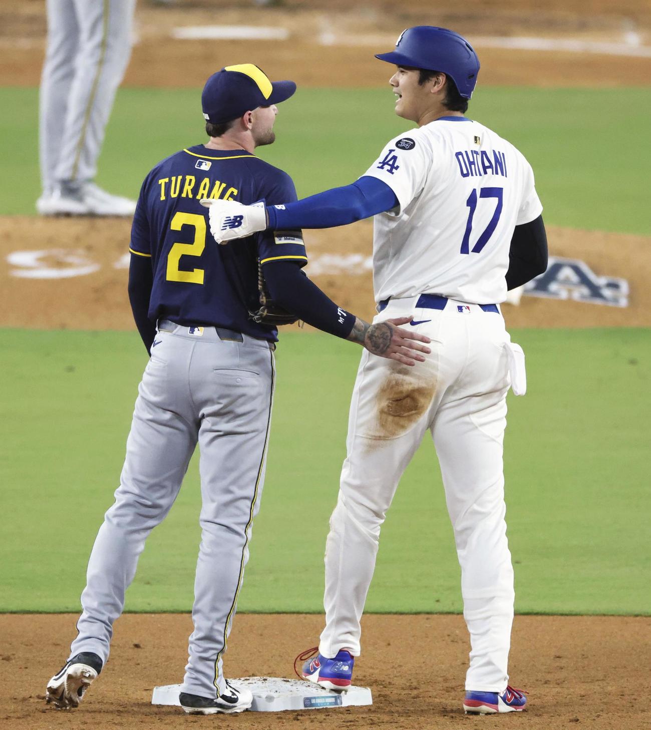 6回、二盗のとき送球がドジャース大谷に当たったが、その後ブルワーズの二塁手（左）と言葉を交わした（共同）