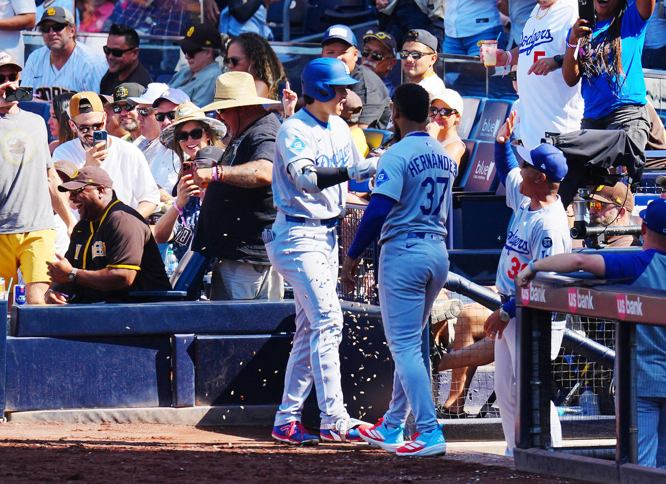 パドレス対ドジャース　9回表ドジャース1死、ソロ本塁打を放った大谷（中央左）はベンチ横のパドレスファン（左）とタッチを交わしナインの出迎えを受ける（撮影・垰建太）