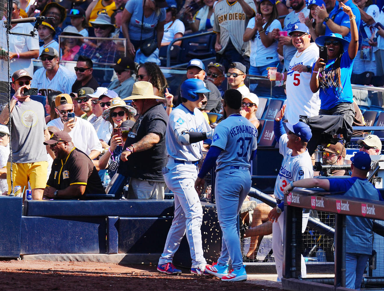 パドレス対ドジャース　9回表ドジャース1死、ソロ本塁打を放った大谷（中央左）はベンチ横のパドレスファン（左）とタッチを交わしナインの出迎えを受ける（撮影・垰建太）