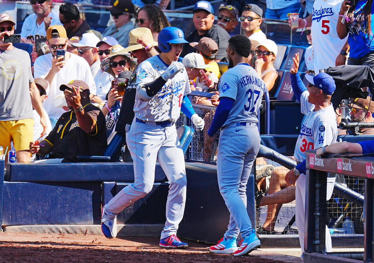 パドレス対ドジャース　9回表ドジャース1死、ソロ本塁打を放った大谷（中央左）はベンチ横のパドレスファン（左）とタッチを交わしナインの出迎えを受ける（撮影・垰建太）