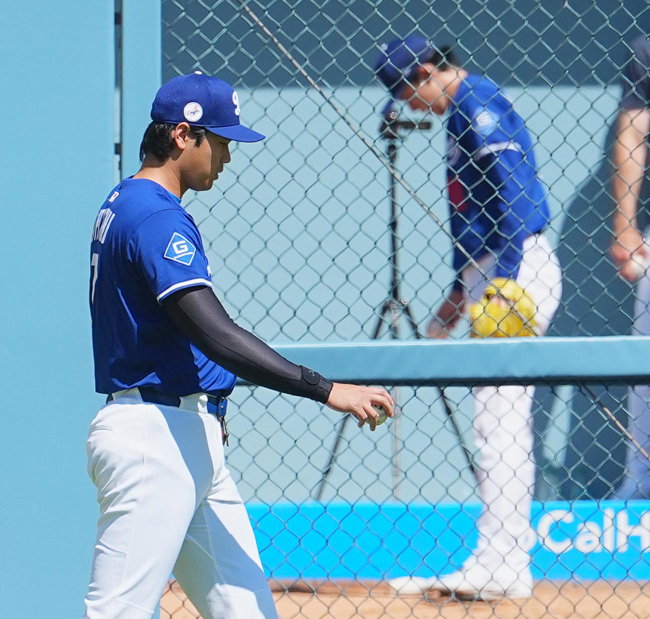 ドジャース対ダイヤモンドバックス　試合前、ブルペンで投球練習をする佐々木（後方）を横目にフィールドに登場するドジャース大谷（撮影・菅敏）