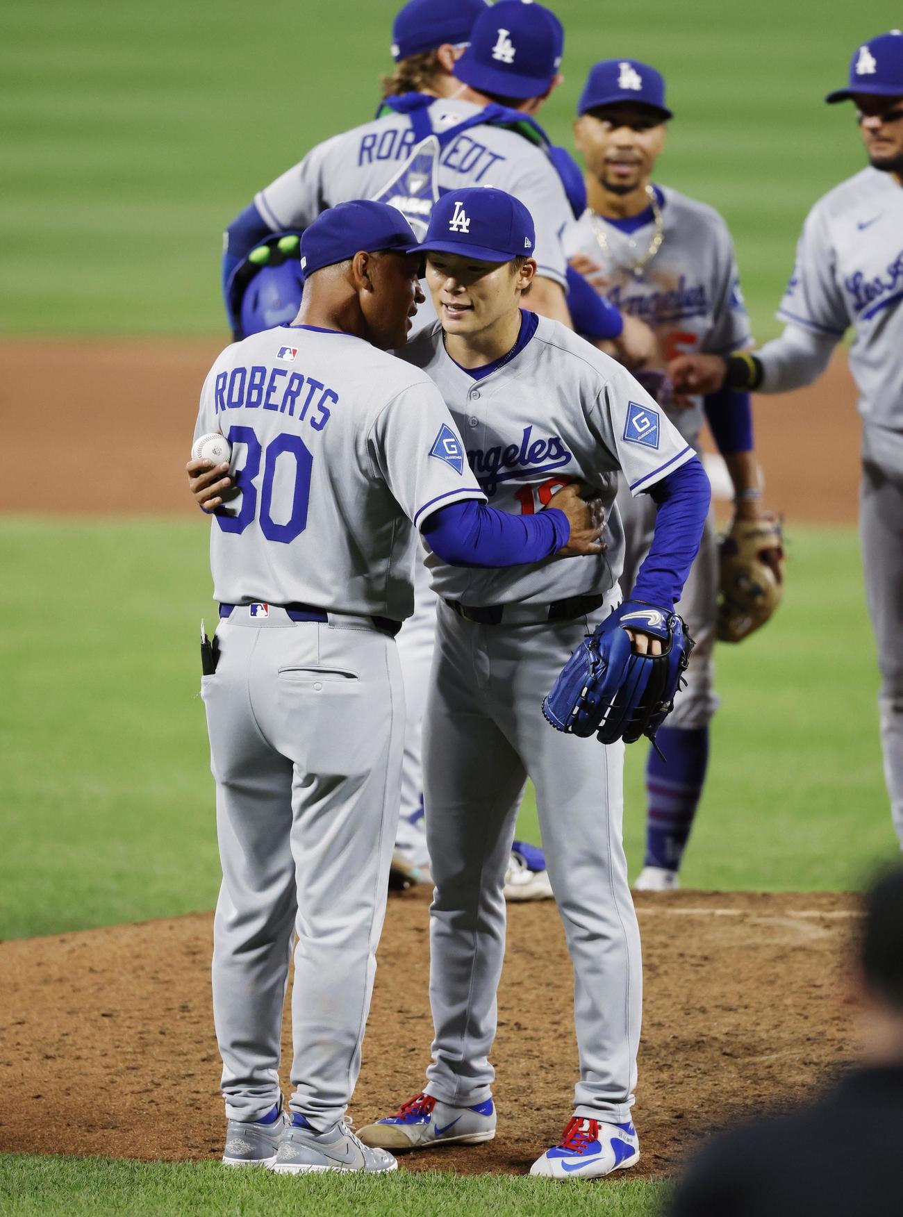 オリオールズ戦の9回、無安打無得点試合まであと1人の場面で本塁打を浴び、ロバーツ監督（手前左）にハグされ降板するドジャース山本（共同）