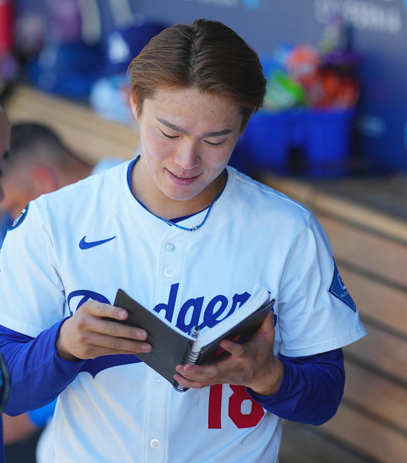 2025年8月31日のダイヤモンドバックスとの試合中、ベンチでノートを読むドジャース山本由伸