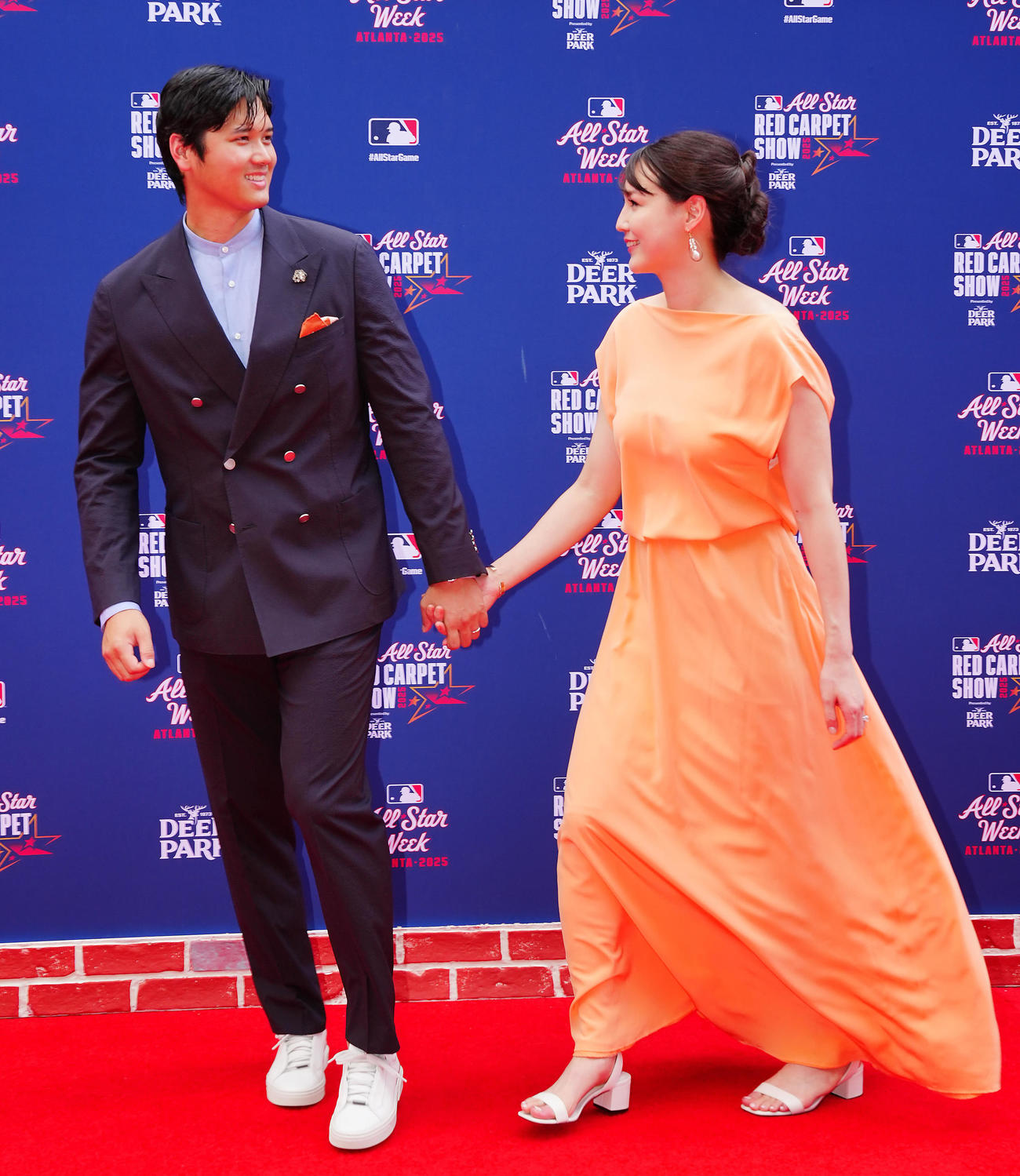 レッドカーペットでドジャース大谷（左）はドレス姿の真美子夫人と手をつなぎ笑顔を見せる（2025年7月）