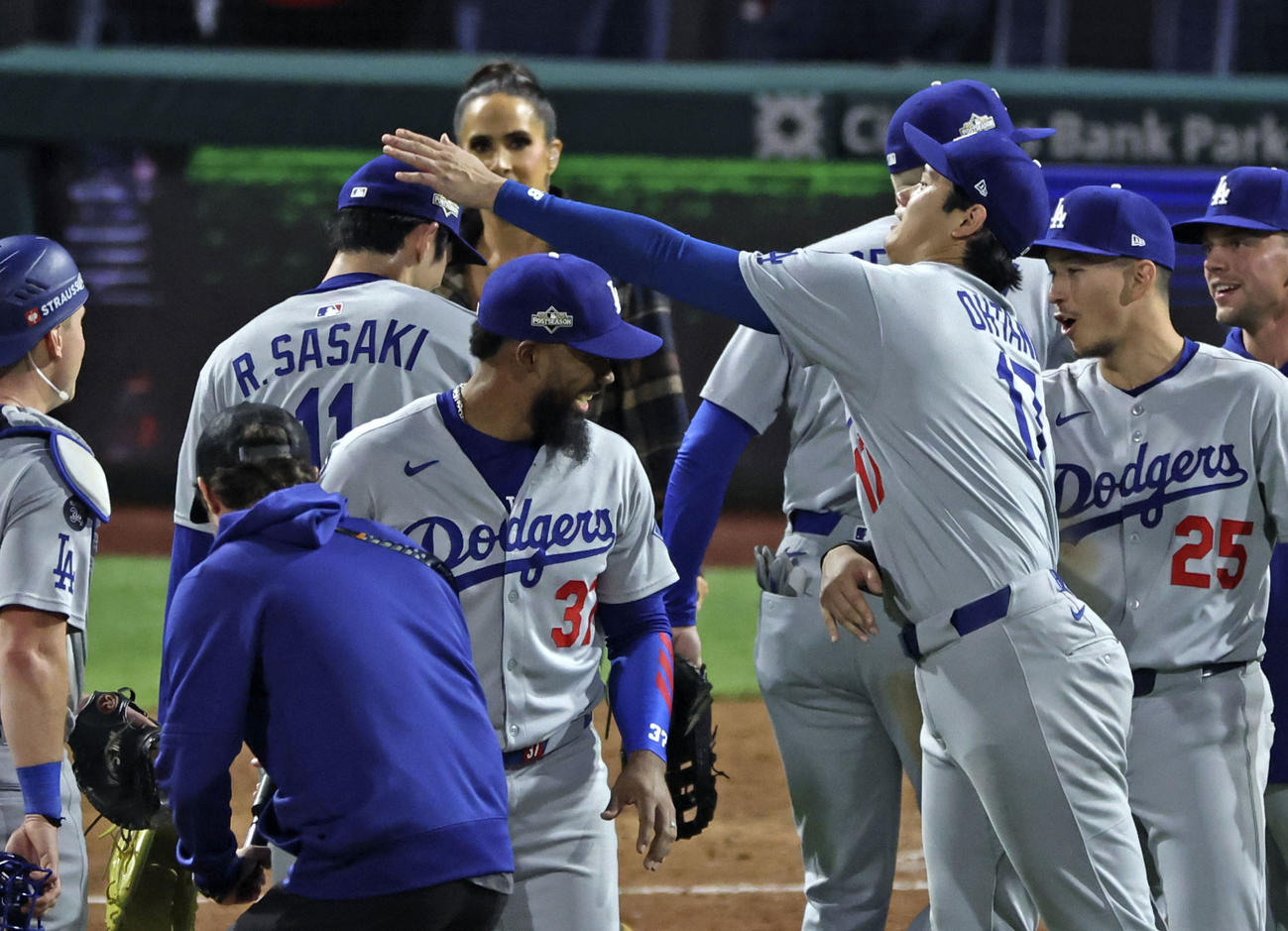 フィリーズに勝利し、初セーブを挙げた佐々木（左奥）を迎えるドジャース大谷（共同）